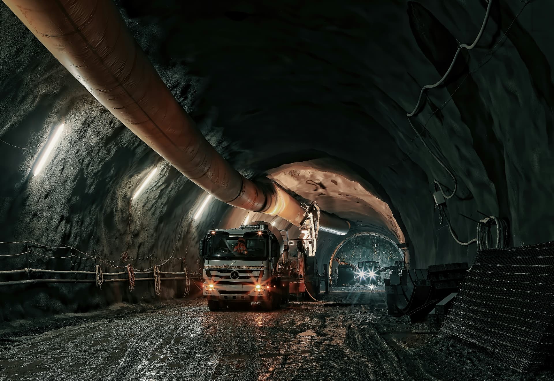 Haulage truck driving through a lit underground mine tunnel